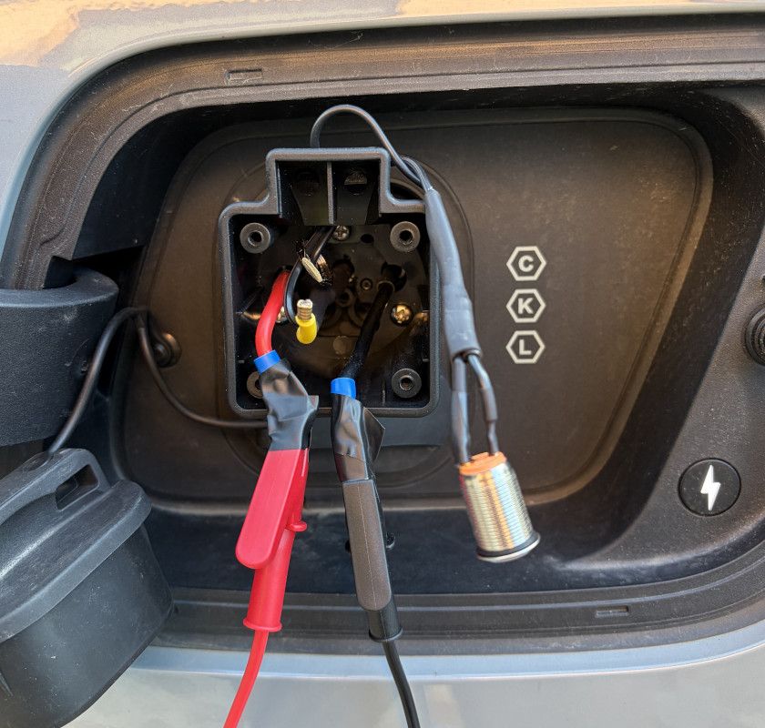 Picture #1 with hacked adapter plugged into the car. Button hanging. Multimeter connected using crocodile clips.