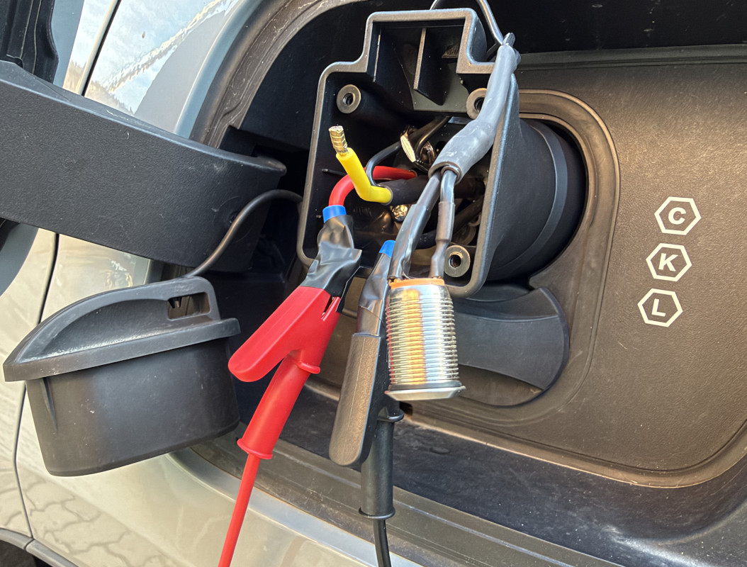 Picture #2 with hacked adapter plugged into the car. Button hanging. Multimeter connected using crocodile clips.